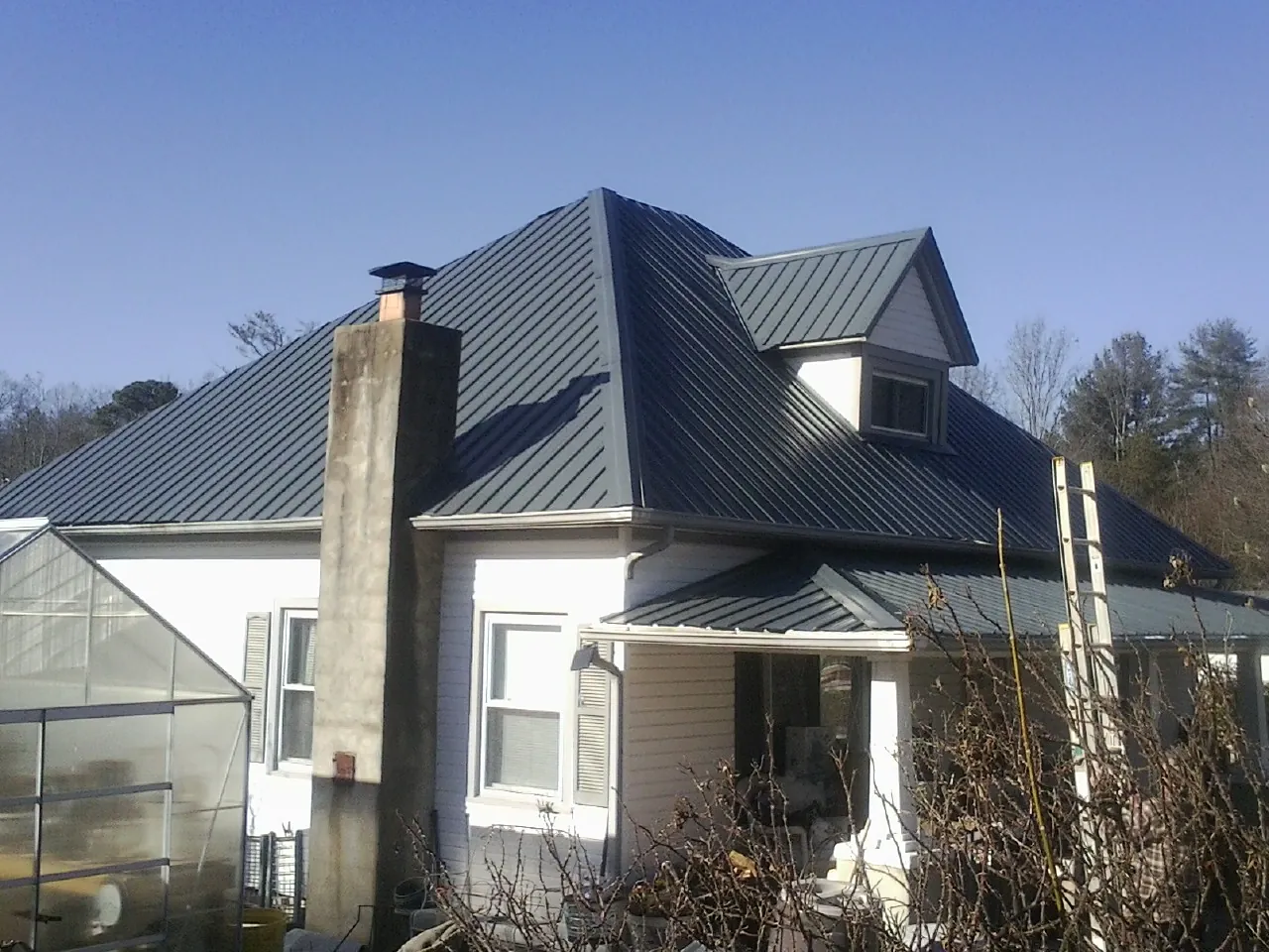 Dark blue standing seam metal roof on a white farmhouse with dormer — Slate & Tile Roof Repair by Roofing Brothers in Stillman Valley