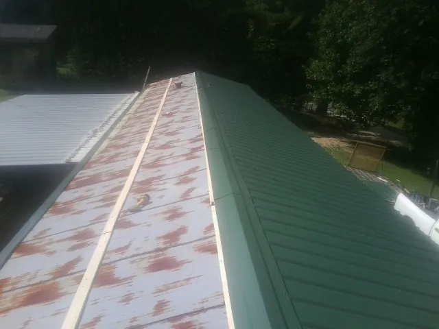Old rusted panels beside newly installed green metal roofing — Wind Damage Roof Repair by Roofing Brothers in Stillman Valley