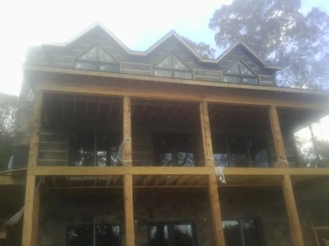Dormers and porch framing on a large log home under construction — Roof Coating work by our crew in Stillman Valley