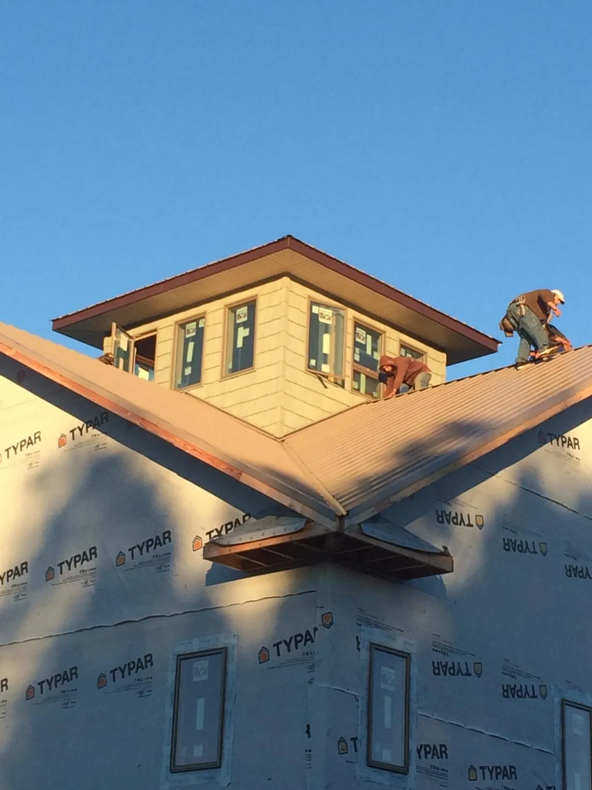 Roofers working around a rooftop cupola on a new metal roof at sunset — Roof Waterproofing in Stillman Valley by Roofing Brothers